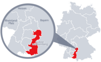 Diese Grafik zeigt eine Karte von Deutschland mit einer detaillierten Ansicht der Region Südostwürttemberg. Südostwürttemberg ist in Rot hervorgehoben und liegt im südlichen Teil Deutschlands. Ein Lupensymbol vergrößert diesen Bereich, um die Lage genauer darzustellen. 